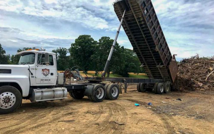 DBE truck dumping pile of tree debris after storm clean up