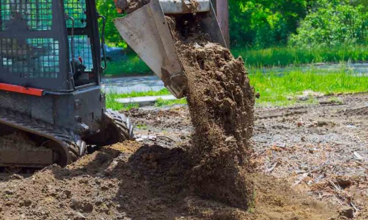 A bulldozer filling the ground with soil to level the surface